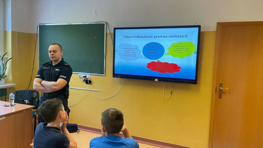 Spotkanie z policjantem, w tle policjant i uczniowie